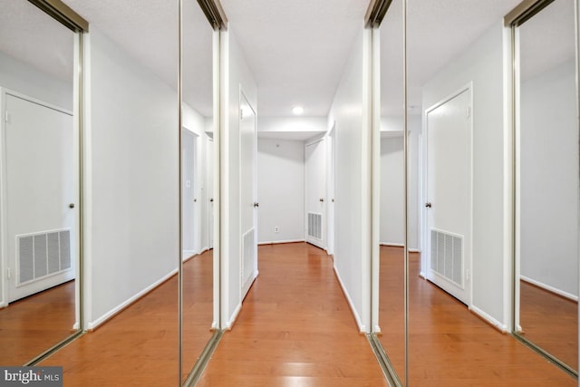 hallway with light wood finished floors and visible vents