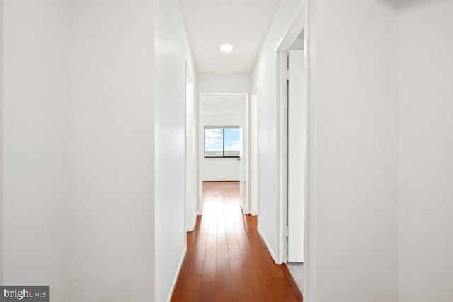 corridor with wood finished floors and baseboards