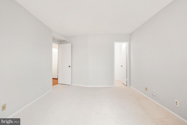 spare room with light carpet and baseboards