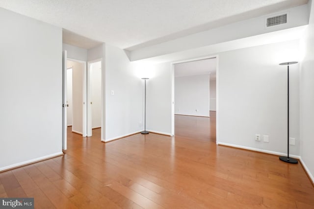 spare room with visible vents, baseboards, and hardwood / wood-style flooring