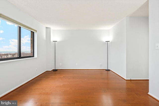 empty room with baseboards and wood finished floors