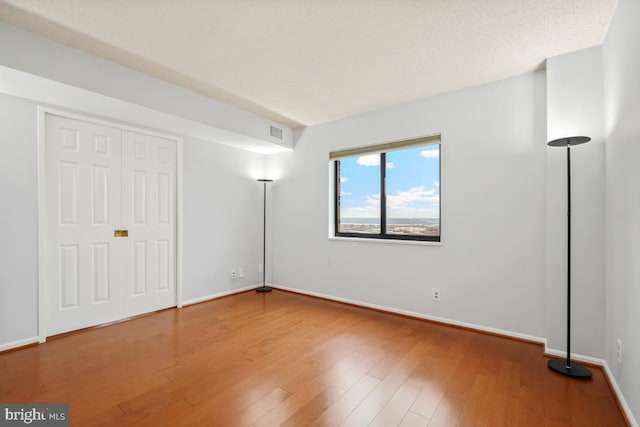 unfurnished bedroom with baseboards, visible vents, and wood finished floors