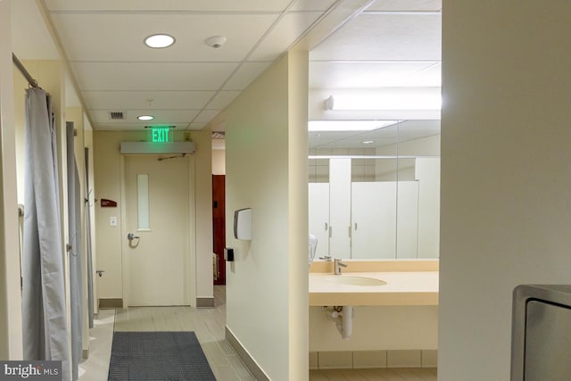 bathroom featuring a paneled ceiling, visible vents, a sink, tile patterned flooring, and walk in shower