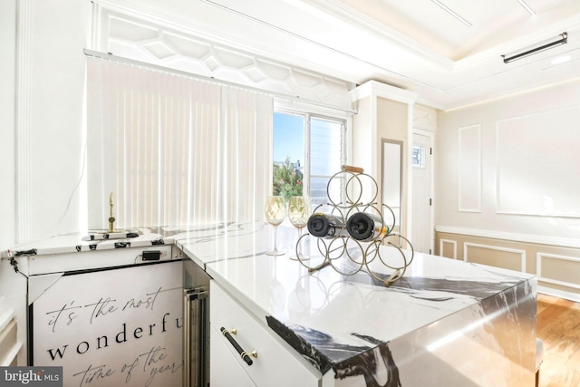 kitchen with crown molding, white cabinetry, hardwood / wood-style floors, and light stone countertops