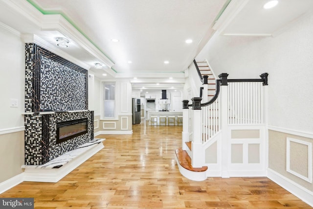 exercise room with a tiled fireplace, crown molding, and wood-type flooring