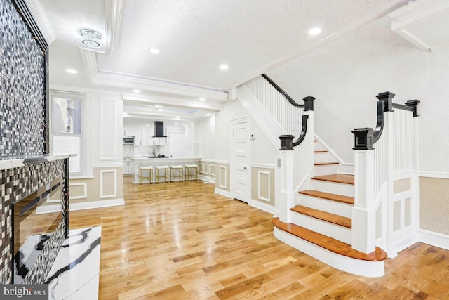 interior space featuring crown molding, sink, wood-type flooring, and a textured ceiling