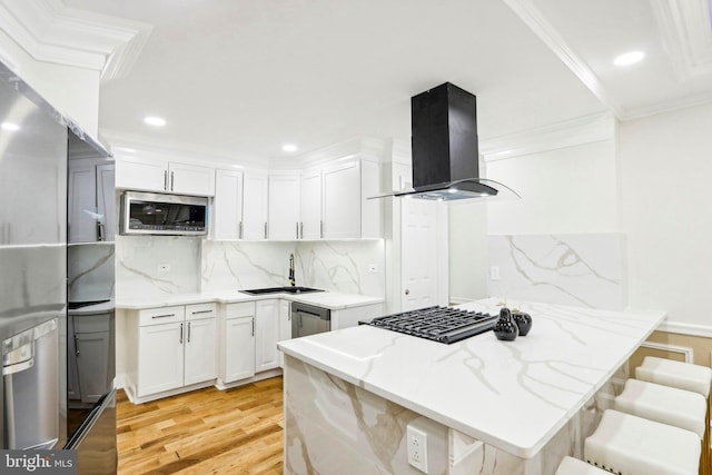 kitchen featuring white cabinetry, light stone countertops, range hood, a breakfast bar, and appliances with stainless steel finishes