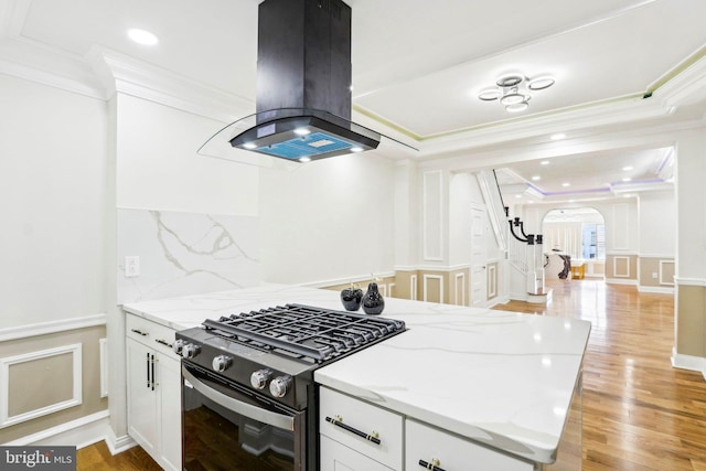 kitchen with white cabinets, island exhaust hood, light stone countertops, and black gas range oven