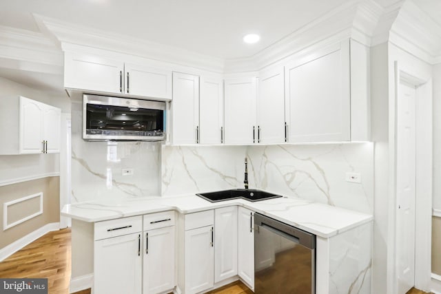 kitchen featuring sink, light hardwood / wood-style flooring, appliances with stainless steel finishes, tasteful backsplash, and white cabinetry