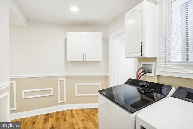 laundry area with light hardwood / wood-style floors, cabinets, and separate washer and dryer