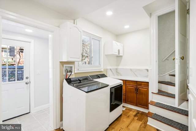 laundry area featuring washer and dryer, plenty of natural light, cabinets, and light hardwood / wood-style flooring