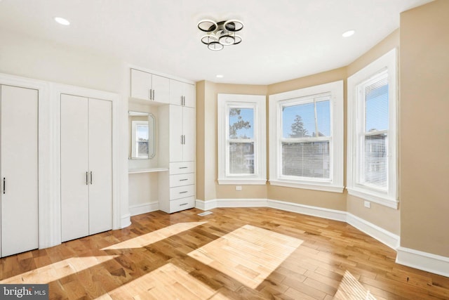 unfurnished bedroom with two closets and light hardwood / wood-style floors