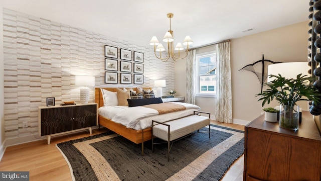 bedroom with light hardwood / wood-style floors and a notable chandelier