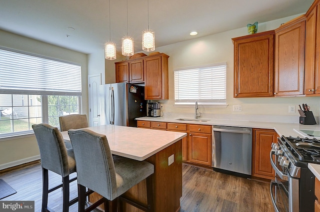 kitchen with decorative light fixtures, a healthy amount of sunlight, dark wood-type flooring, and appliances with stainless steel finishes