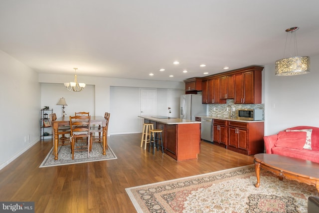 kitchen with decorative backsplash, appliances with stainless steel finishes, a notable chandelier, a center island, and hanging light fixtures