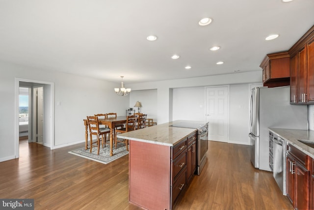 kitchen featuring a center island, hanging light fixtures, a notable chandelier, light stone counters, and stainless steel appliances