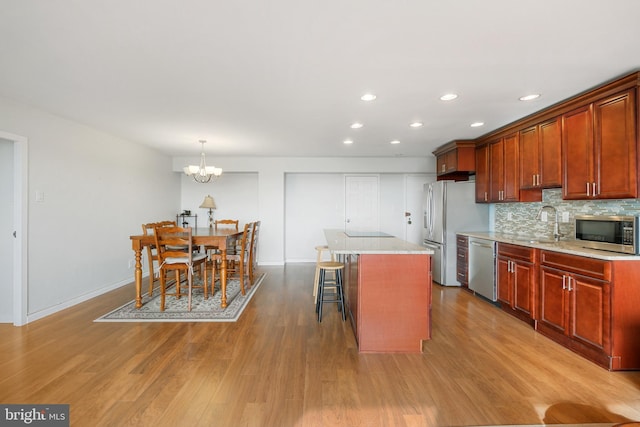 kitchen with a notable chandelier, decorative light fixtures, a breakfast bar area, a kitchen island, and appliances with stainless steel finishes