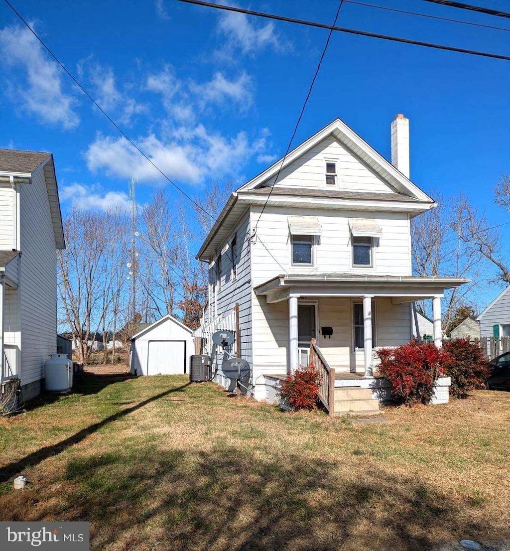 view of front of property featuring central AC, a garage, an outdoor structure, and a front lawn