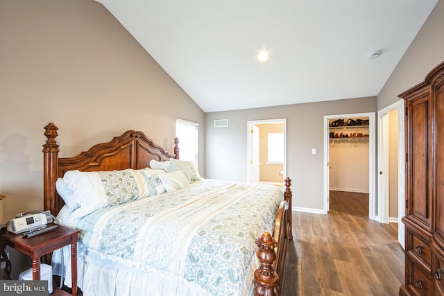 bedroom with hardwood / wood-style floors, vaulted ceiling, a spacious closet, and a closet