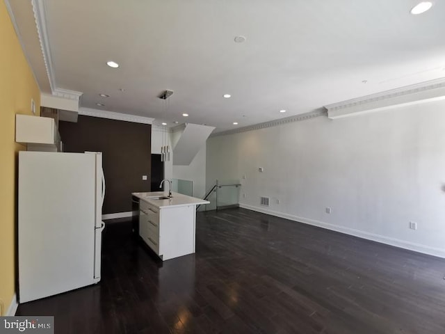 kitchen featuring white fridge, a center island with sink, sink, white cabinetry, and ornamental molding