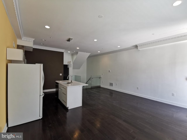 kitchen with decorative light fixtures, sink, a kitchen island with sink, white cabinets, and white refrigerator