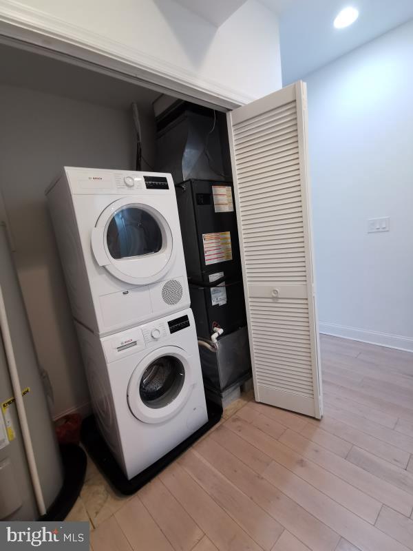 washroom featuring light hardwood / wood-style flooring and stacked washer and dryer