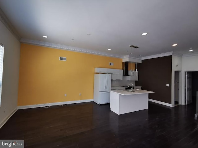 kitchen featuring dark hardwood / wood-style floors, a center island with sink, sink, crown molding, and white refrigerator