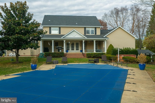 back of house featuring a yard, a covered pool, covered porch, and a patio area