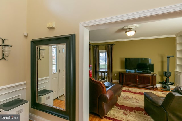 living room with built in shelves, wood-type flooring, and ornamental molding