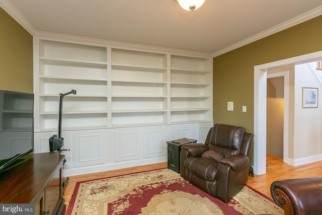 sitting room featuring ornamental molding, light hardwood / wood-style floors, and built in features