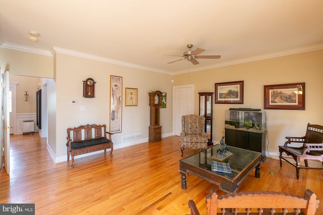 living room featuring ornamental molding, ceiling fan, and light wood-type flooring