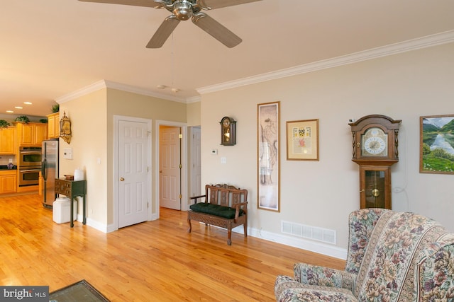 sitting room with ornamental molding, ceiling fan, and light wood-type flooring