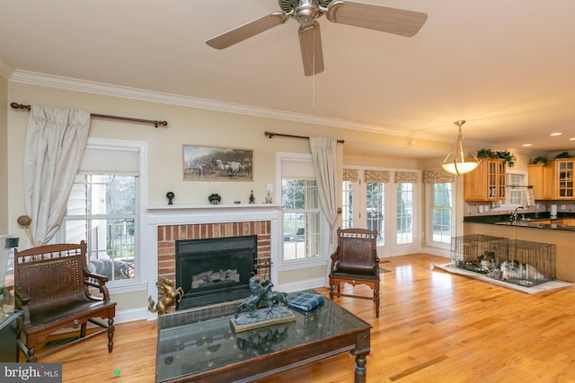 living room featuring plenty of natural light, sink, light hardwood / wood-style floors, and a brick fireplace