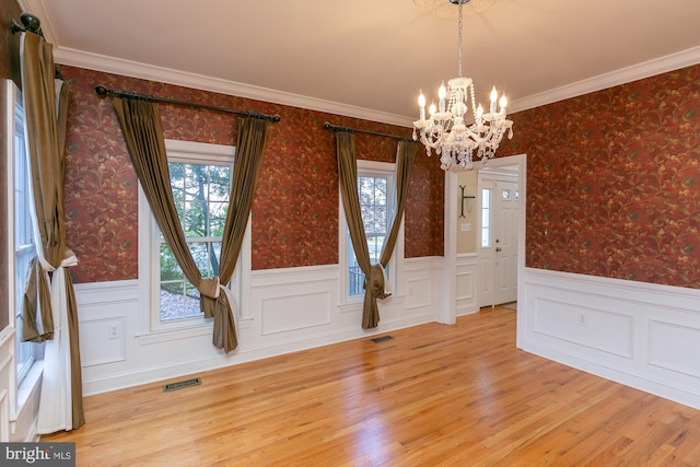 interior space with crown molding, plenty of natural light, an inviting chandelier, and light hardwood / wood-style floors