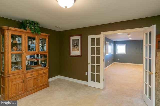 unfurnished room featuring french doors and light carpet