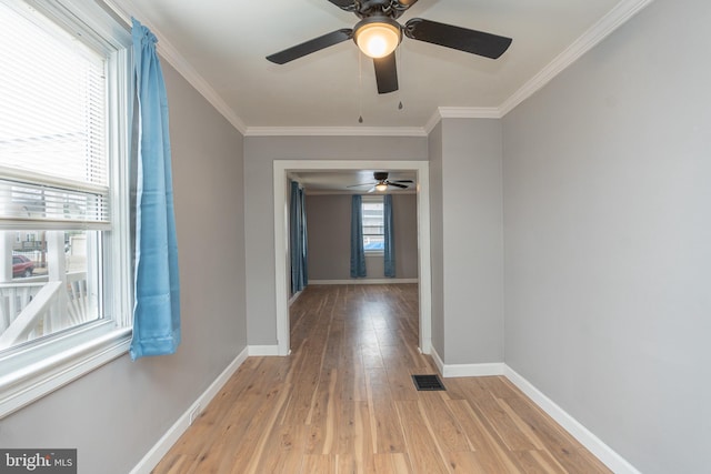 hallway with light wood-type flooring, crown molding, and a healthy amount of sunlight