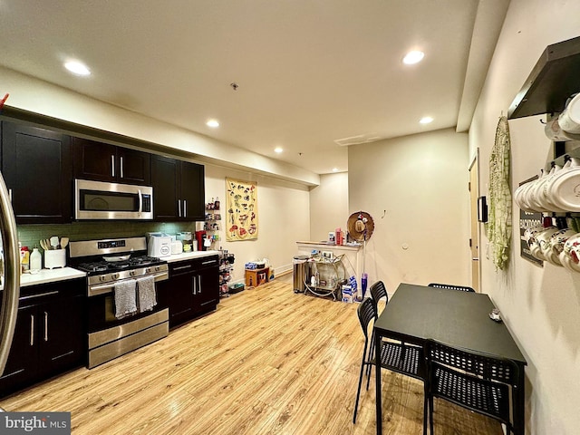 kitchen with decorative backsplash, appliances with stainless steel finishes, and light hardwood / wood-style flooring