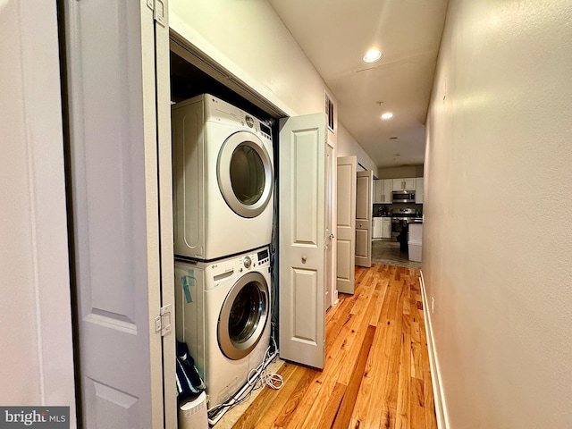 clothes washing area featuring light wood-type flooring and stacked washer and clothes dryer