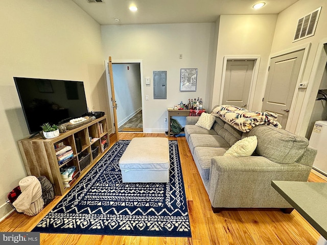 living room with electric panel, light hardwood / wood-style flooring, and a high ceiling