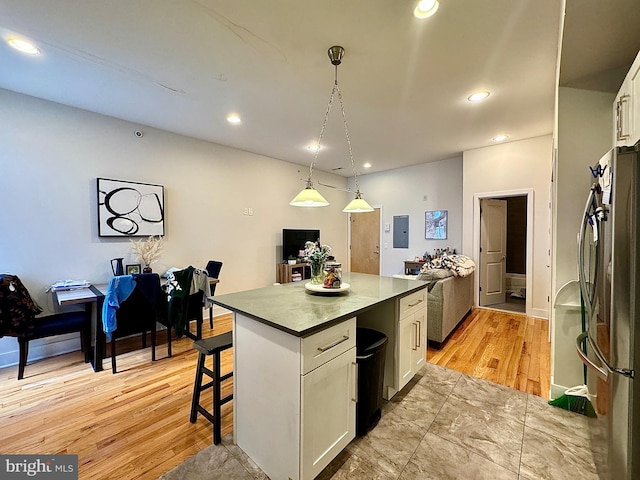 kitchen featuring white cabinets, stainless steel fridge, a kitchen island, and a breakfast bar area