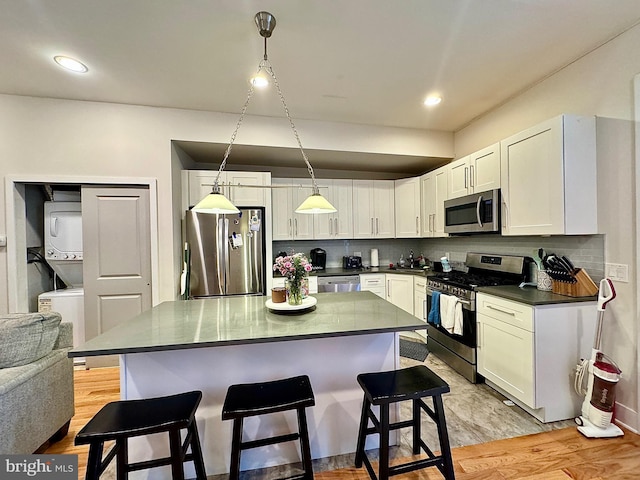 kitchen featuring decorative light fixtures, stainless steel appliances, white cabinetry, and light hardwood / wood-style floors