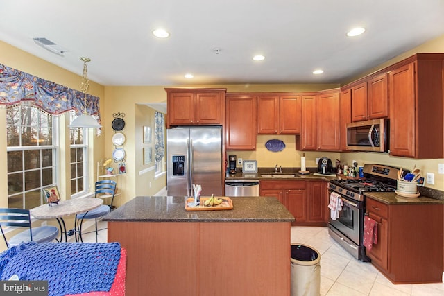 kitchen with a center island, light tile patterned floors, stainless steel appliances, and sink