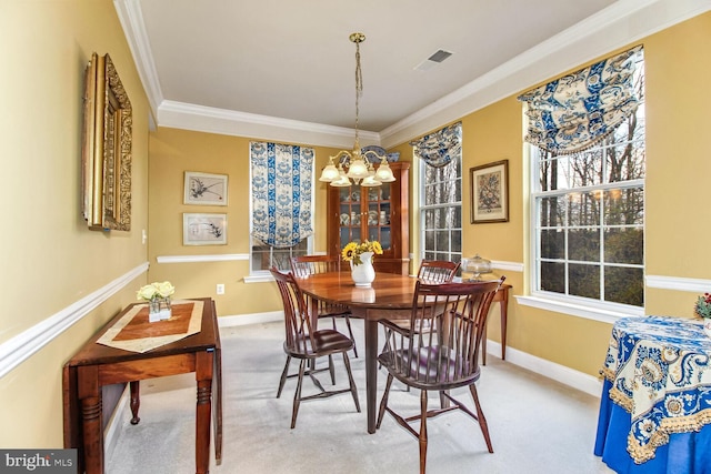 carpeted dining space featuring ornamental molding and an inviting chandelier