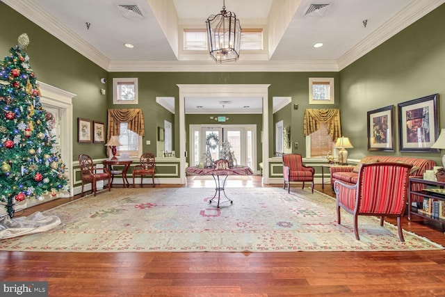 interior space featuring ornamental molding, a towering ceiling, a chandelier, and wood-type flooring