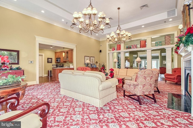 living room with a chandelier, a towering ceiling, a tray ceiling, and ornamental molding