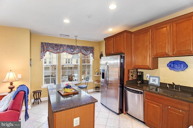 kitchen featuring appliances with stainless steel finishes, sink, decorative light fixtures, a kitchen island, and light tile patterned flooring