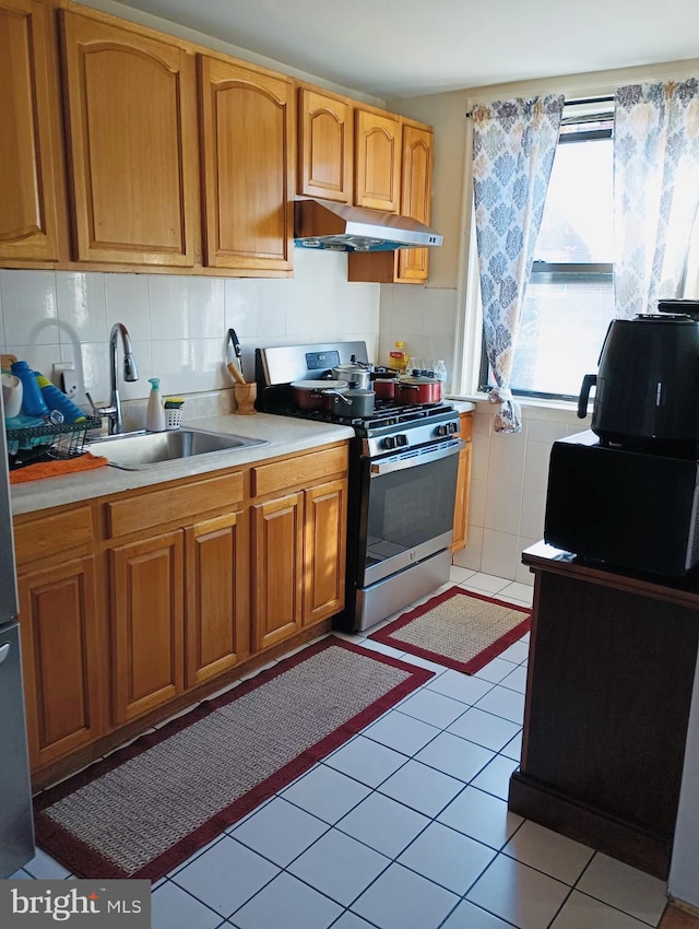 kitchen featuring light tile patterned floors, backsplash, stainless steel gas stove, and sink