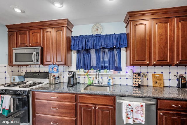 kitchen featuring decorative backsplash, appliances with stainless steel finishes, dark stone counters, and sink