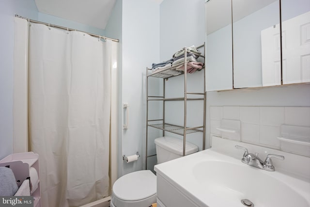 bathroom featuring decorative backsplash, toilet, curtained shower, and sink