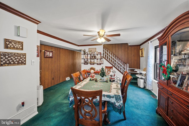 dining area featuring wood walls, ceiling fan, dark carpet, and ornamental molding